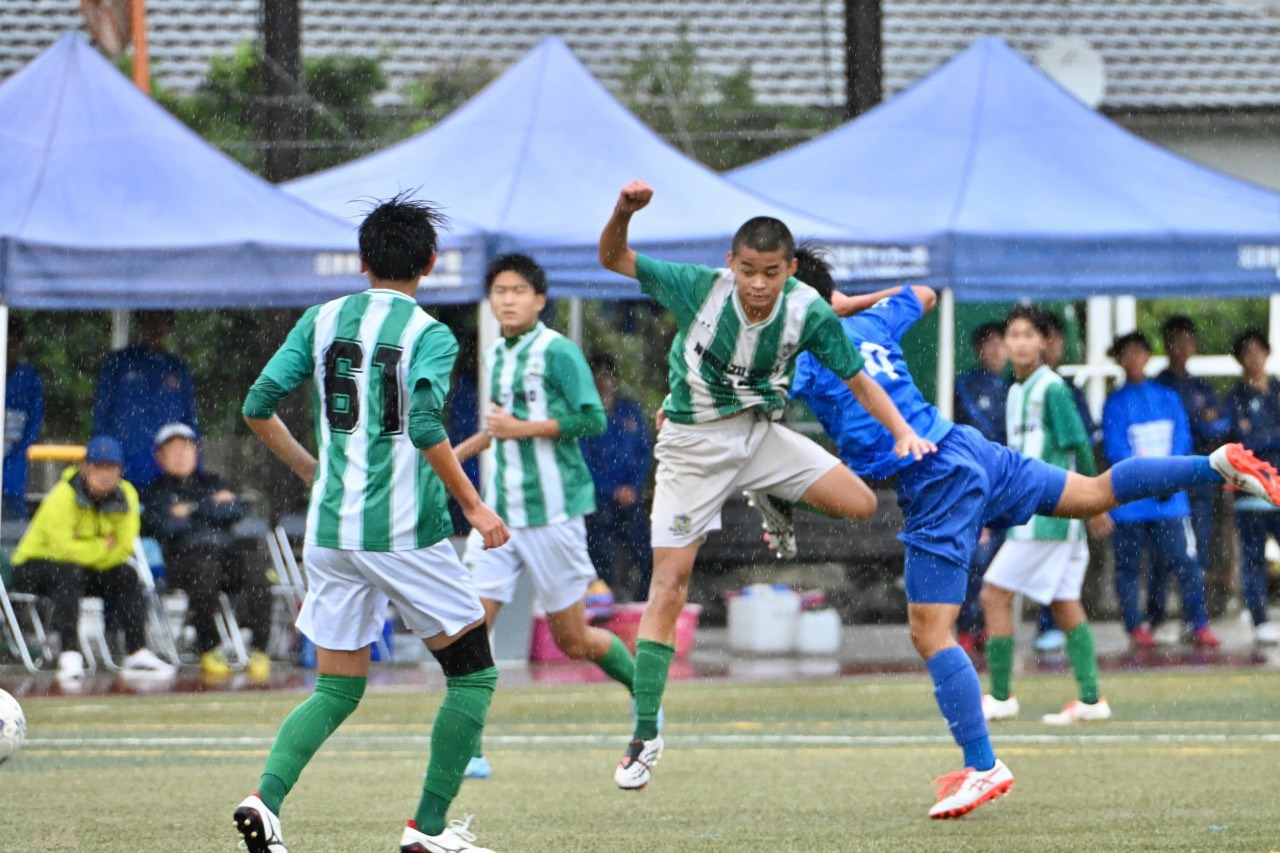 雨の中でボールを競り合う選手たち